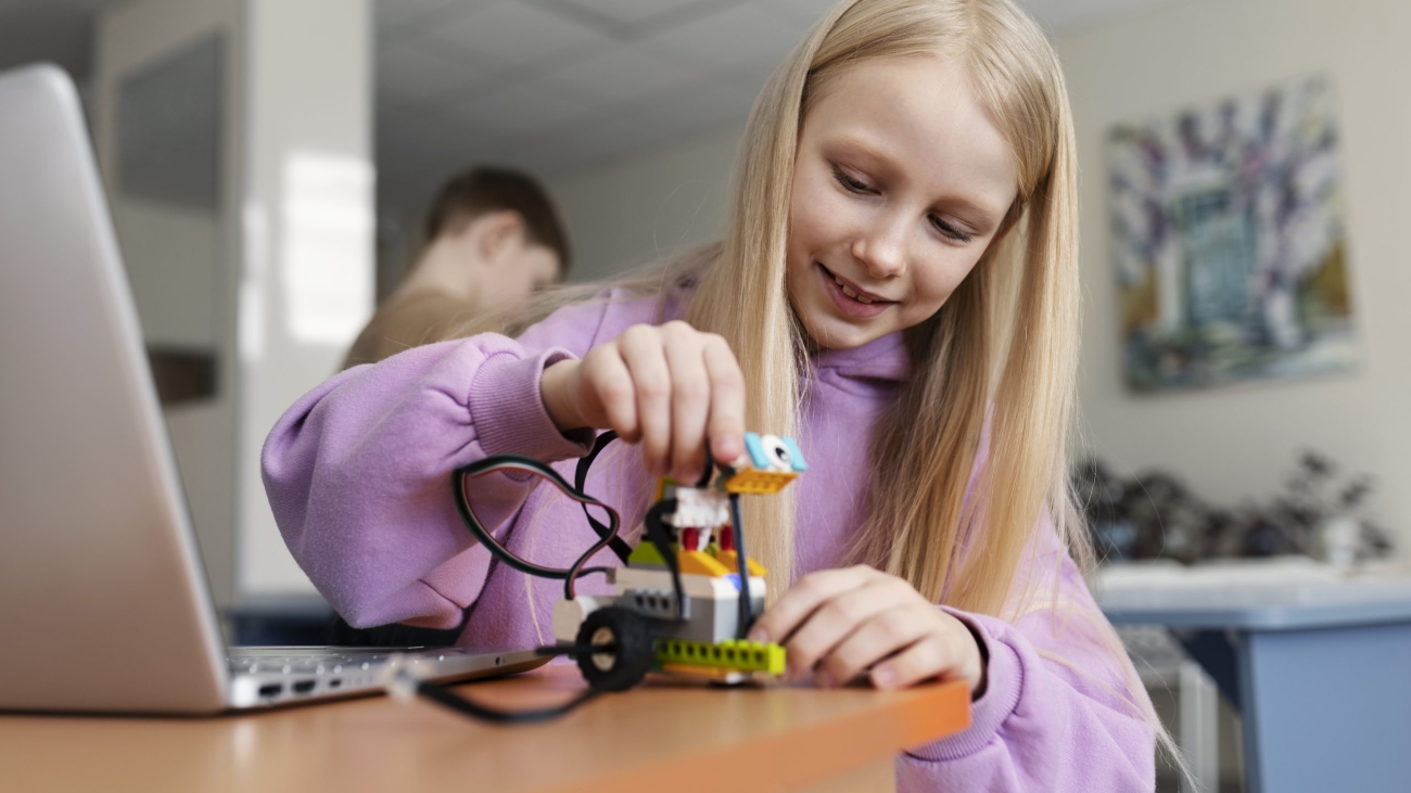 young-girl-using-laptop-electronic-parts-build-robot