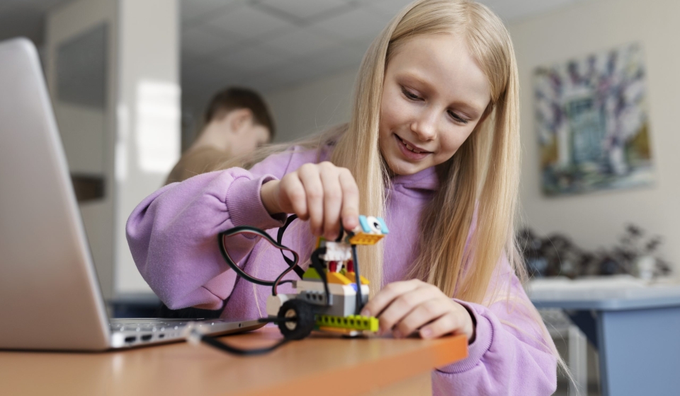 young-girl-using-laptop-electronic-parts-build-robot